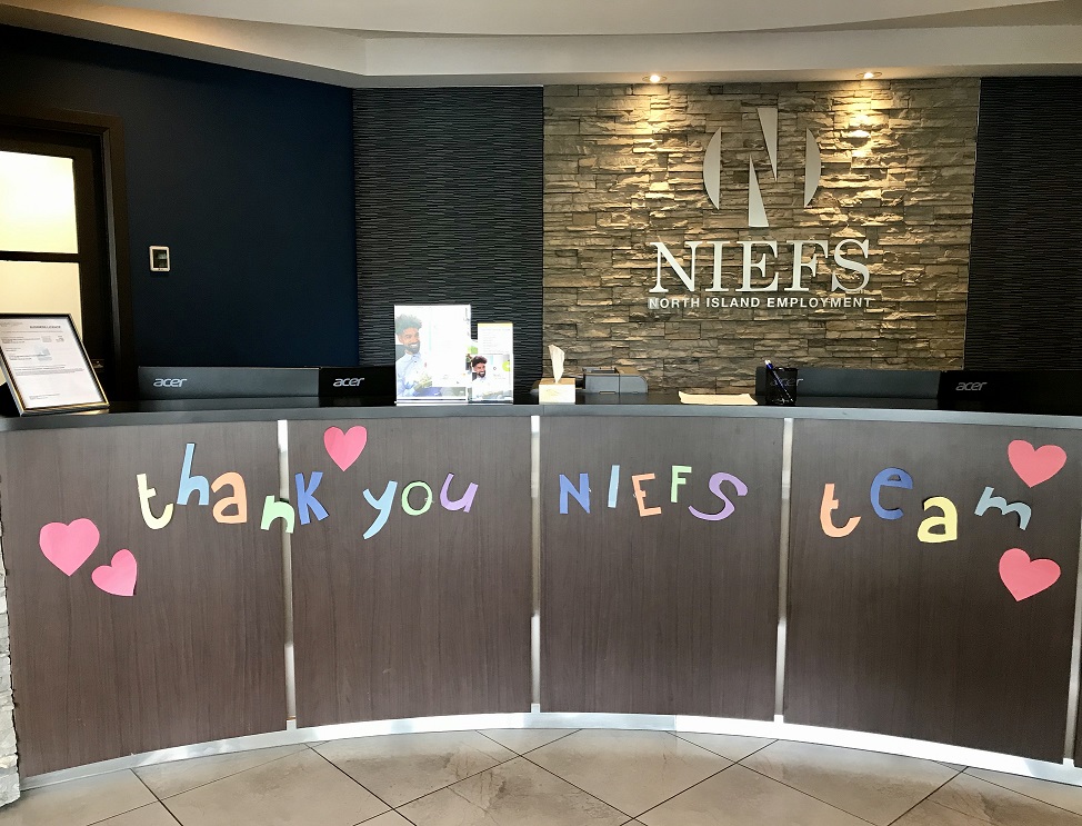 reception desk area with stone wall background that has NIEFS logo on it. 