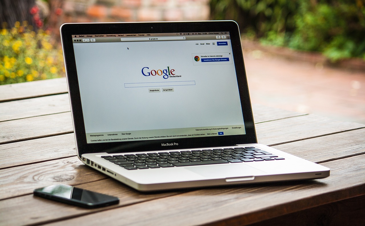 open laptop on a picnic table outside showing Google search page