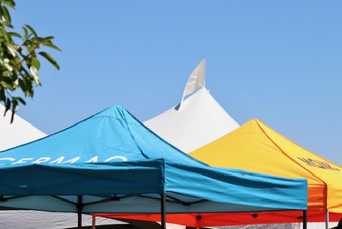 Tops of outdoor blue and yellow canopies on Salmon Day in Campbell River. One reads MOWI, the other CERMAQ
