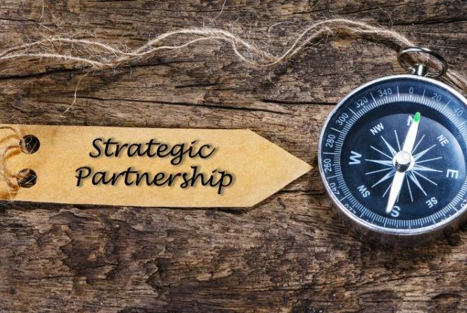 A compass sitting on a board with tag tied to it that reads "Strategic Partnership"