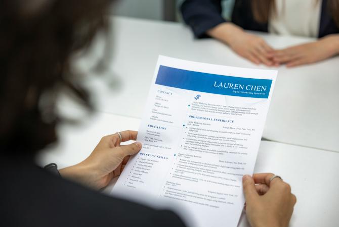 a woman holding a job candidates resume in her hands as she reads it