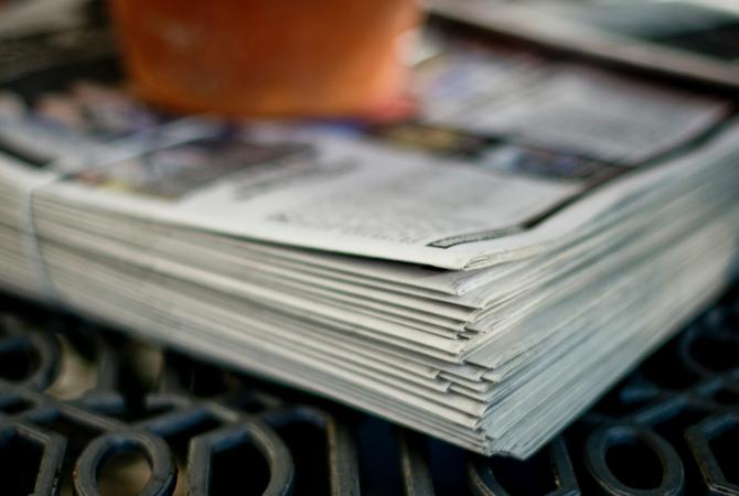 person holding a bundle of newspapers tied together with twine