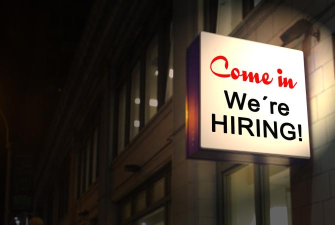 building with neon sign that says come in we're hiring