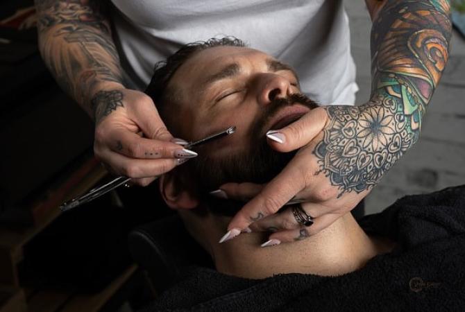 Photo of Leasha MacLennan, Owner/Operator of Black Creek Barber providing a straight razor shave to a client